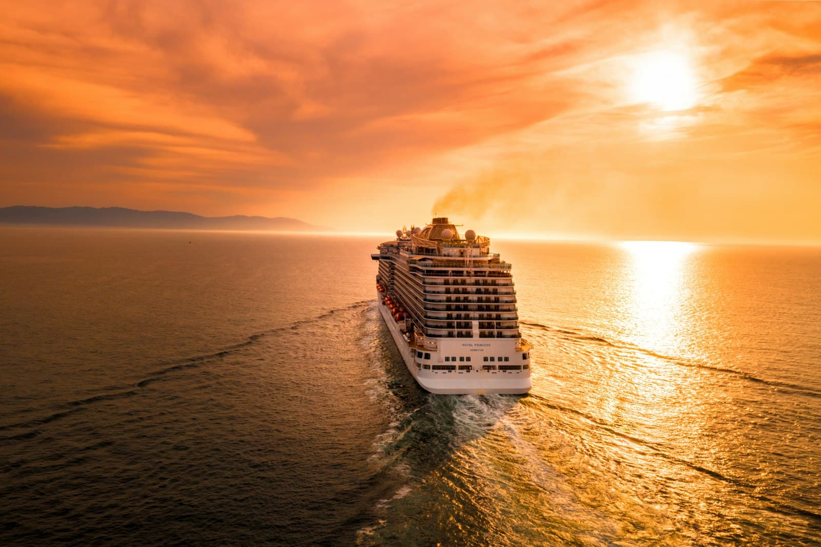 Cruise ship sailing into a golden sunset on open water