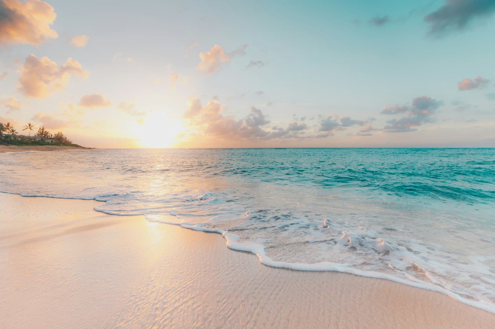 Gentle surf rolling onto a sandy beach at sunrise with turquoise water